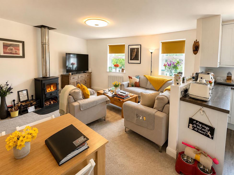 A living room with a stove, sofa, and television at Muddy Boots – Scarpa Kirkby Stephen
