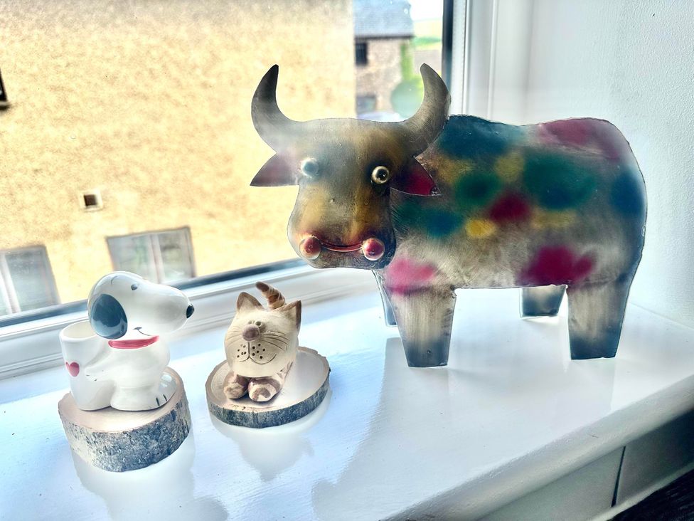 Figurines of a dog, cat, and cow on a windowsill