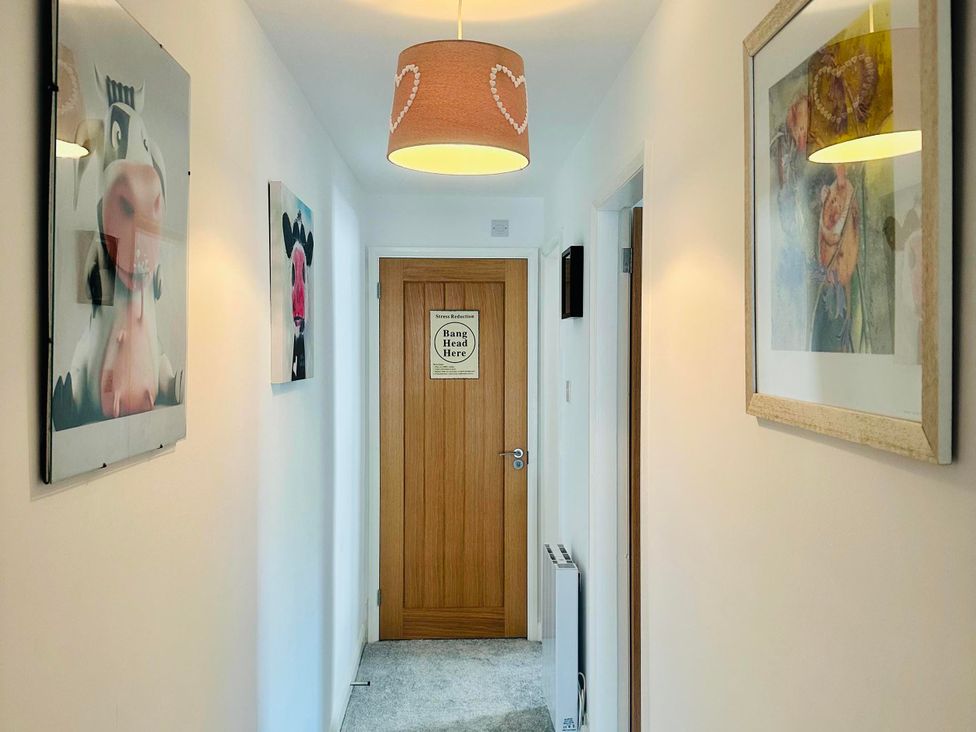 A hallway with wall art and a wooden door at Muddy Boots – Scarpa in Kirkby Stephen