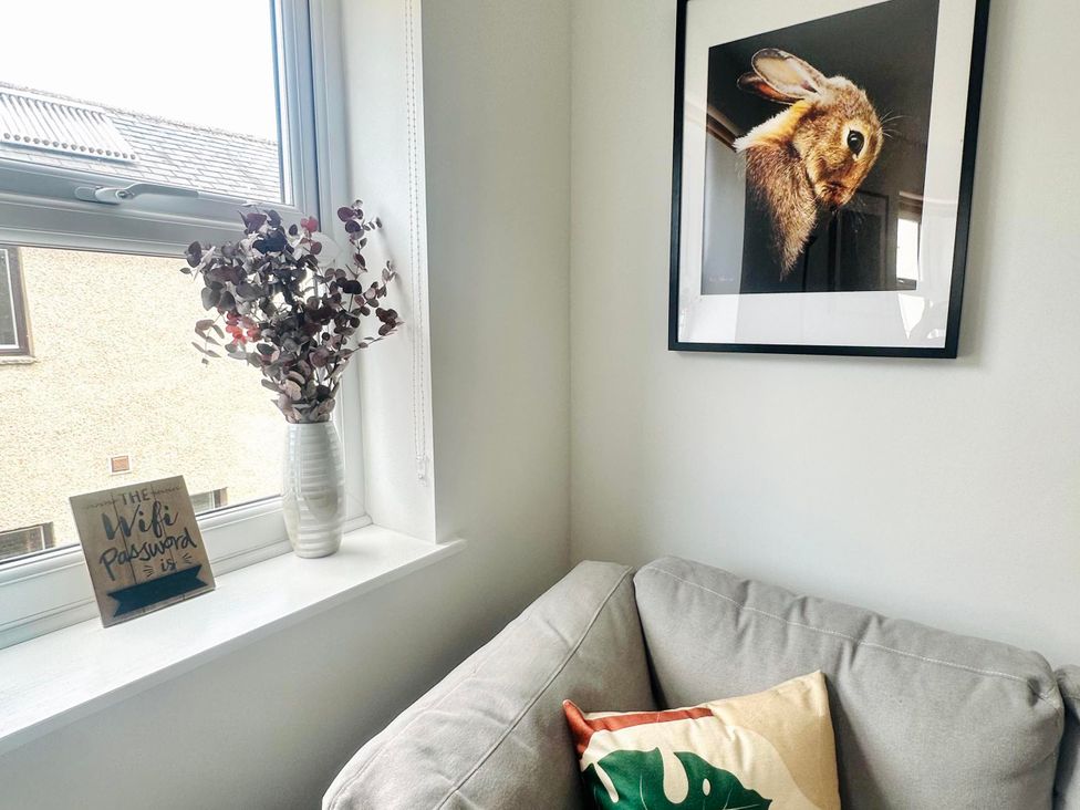 A living room with a sofa and framed picture at Muddy Boots – Scarpa in Kirkby Stephen