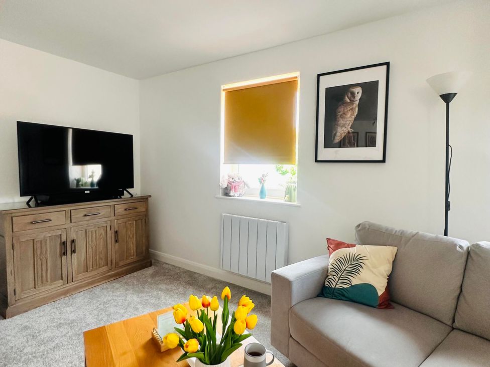 A living room with a television, sofa, and coffee table at Muddy Boots – Scarpa, Kirkby Stephen