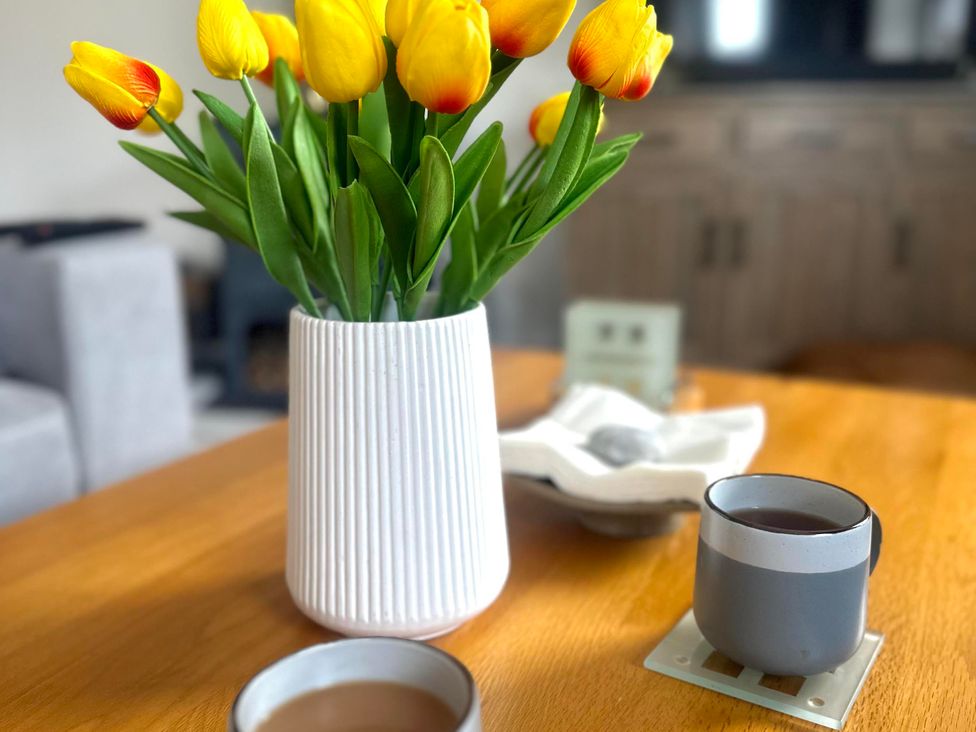 A table with tulips in a vase and coffee cup at Muddy Boots – Scarpa Kirkby Stephen