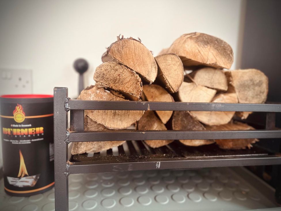 A wood rack with firewood and a fire starter canister at Muddy Boots – Scarpa in Kirkby Stephen