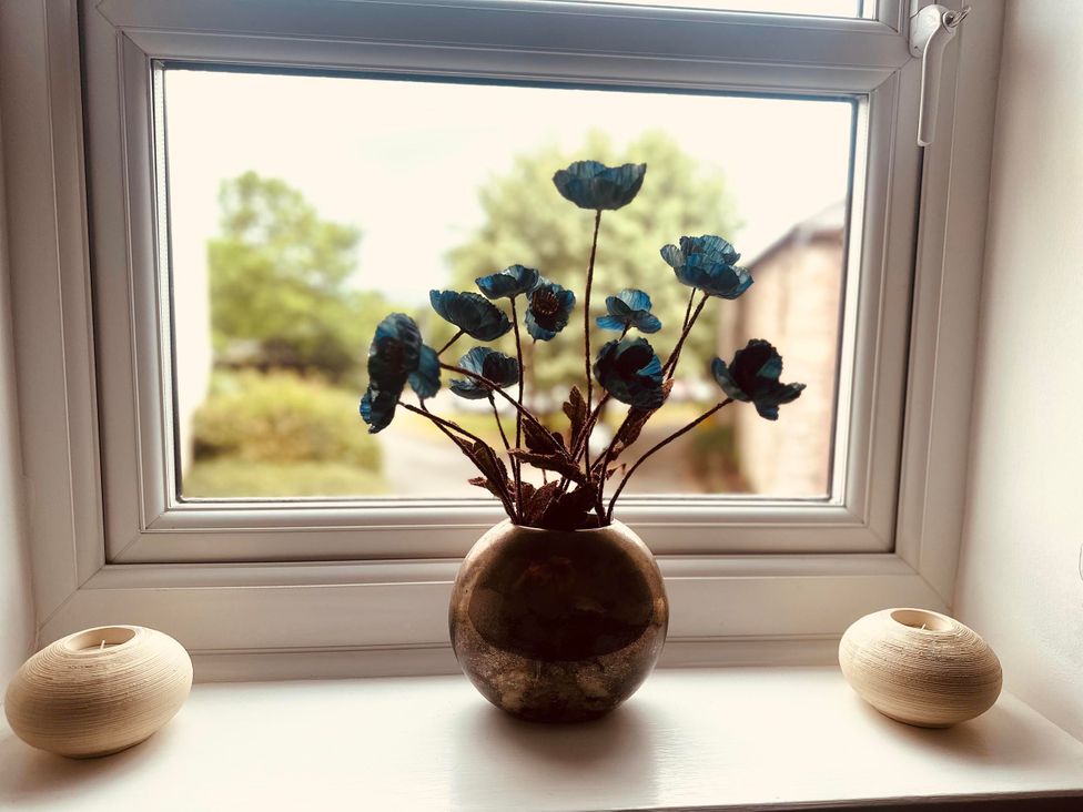 A vase with flowers and candle holders on a windowsill at Muddy Boots – Scarpa Kirkby Stephen
