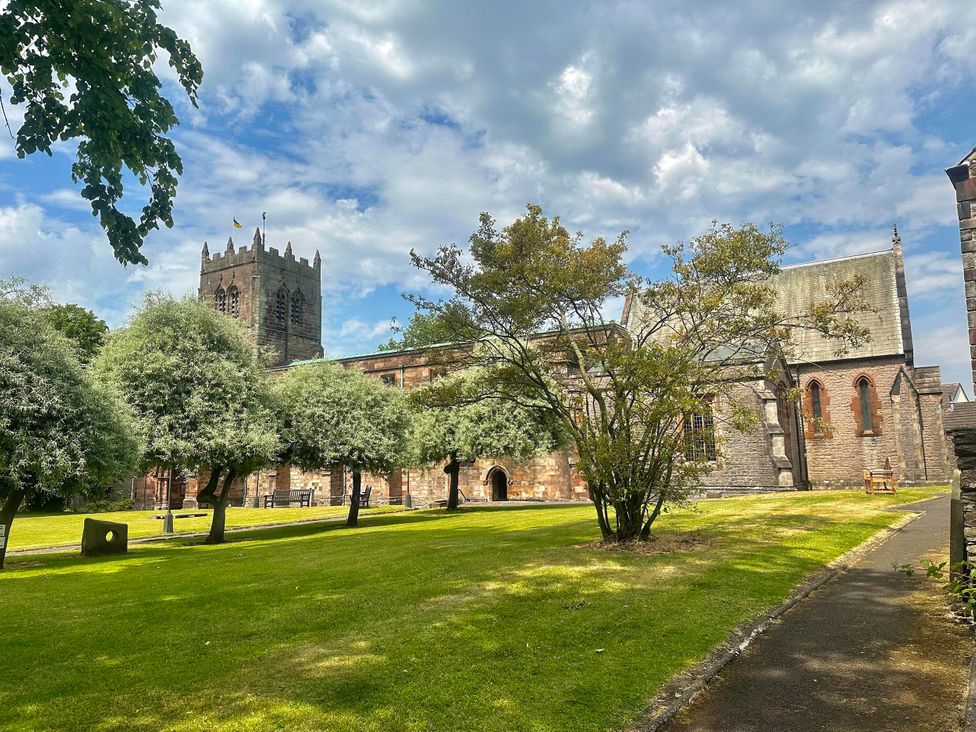 A church with a tower and trees in the surrounding grass area at Muddy Boots – Scarpa, Kirkby Stephen