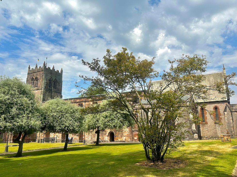 A church with a tower and trees in a garden at Muddy Boots – Scarpa Kirkby Stephen