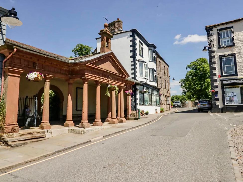 A street view with historic architecture and trees at Muddy Boots – Scarpa in Kirkby Stephen