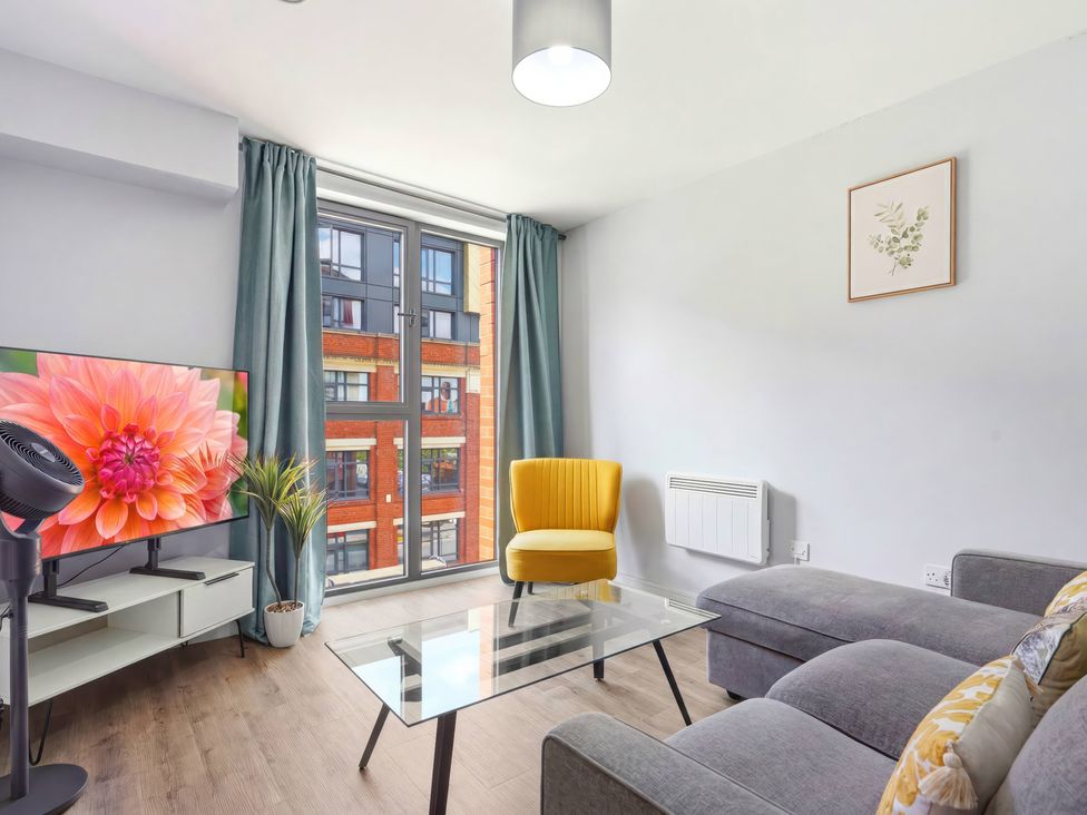 A living room with a yellow chair and television at Apartment 56 in Birmingham