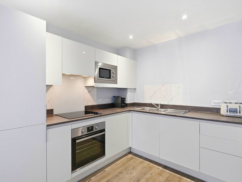 A kitchen with cabinets, microwave, stove, oven, and sink at Apartment 56 in Birmingham