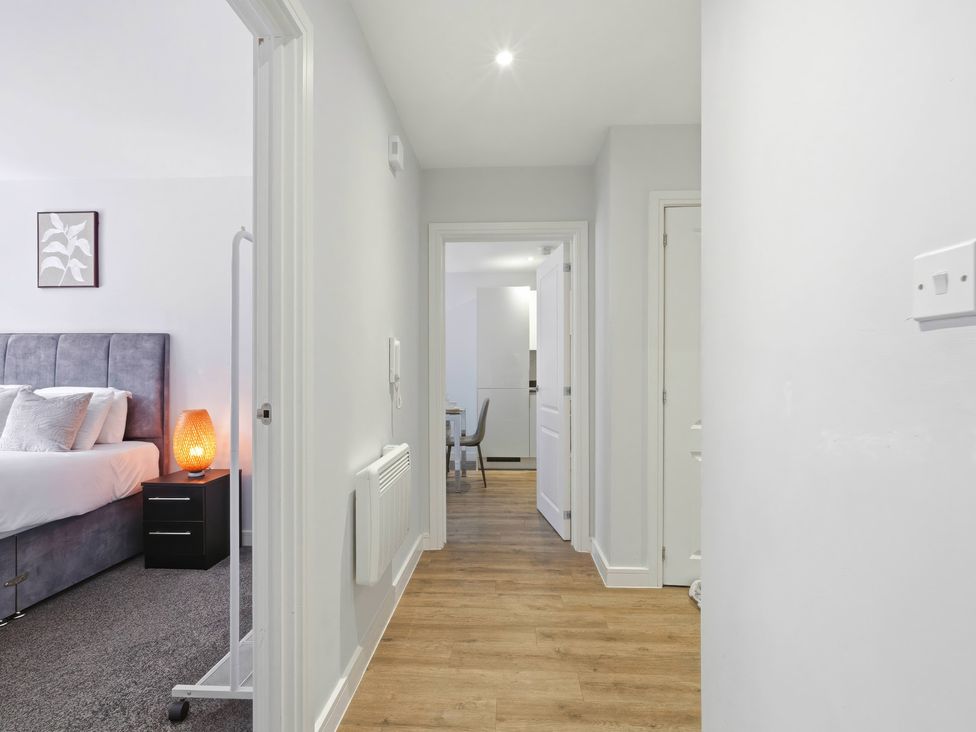 A hallway with a bed, bedside table, and an entrance to the kitchen at Apartment 56 Birmingham