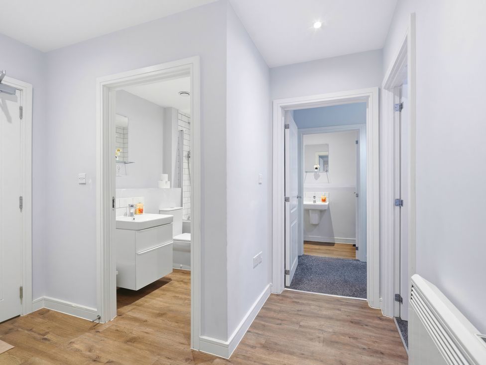 A hallway leading to a bathroom with a sink and mirror at Apartment 56 in Birmingham