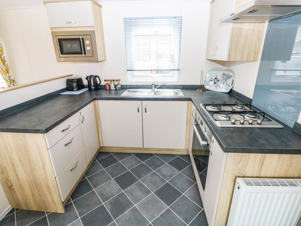 A kitchen with cabinets and a gas stove at Seascape in Haverfordwest