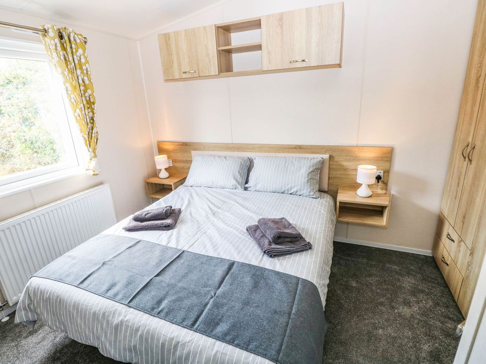 A bedroom featuring a bed with pillows and a bedside table at Seascape in Haverfordwest
