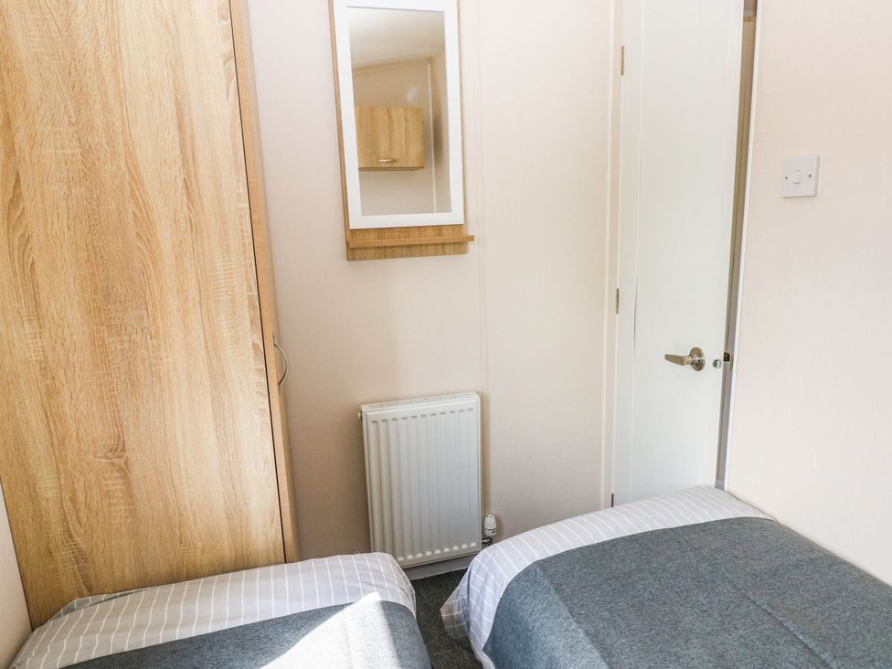 A bedroom with beds and a wardrobe at Seascape in Haverfordwest