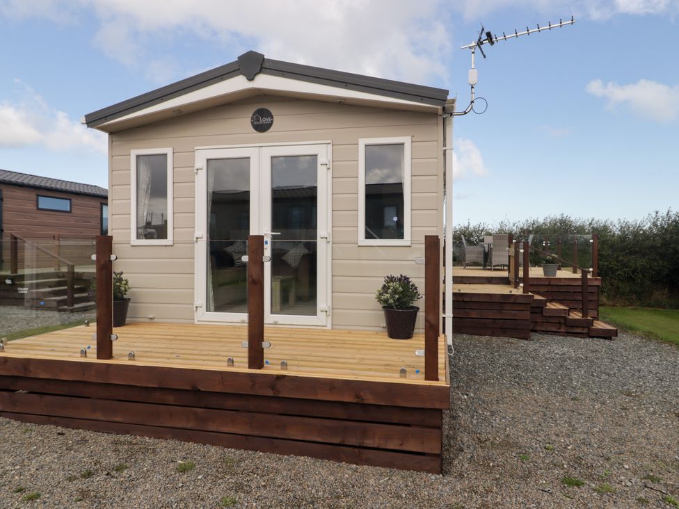 A cabin with a wooden deck and glass railing at Seascape near Little Haven