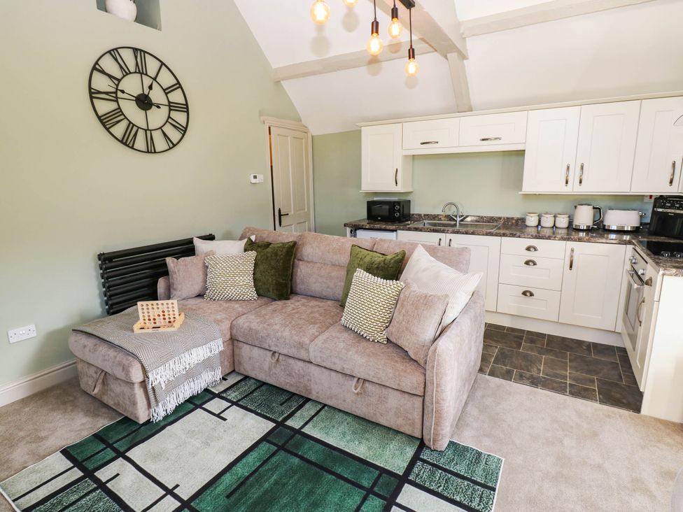 A living room with a sofa and kitchen area at Sands Green in Appleby-In-Westmorland