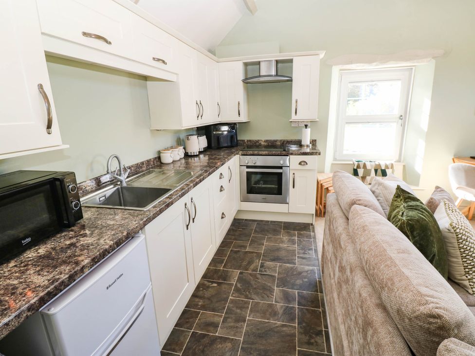 A kitchen with modern appliances and a sofa at Sands Green in Appleby-In-Westmorland
