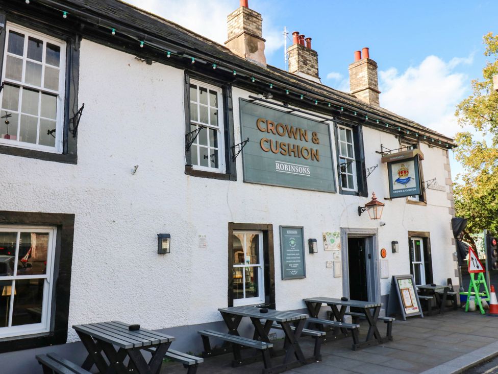 An outdoor view of the Crown & Cushion pub with tables and a sign in Appleby-In-Westmorland