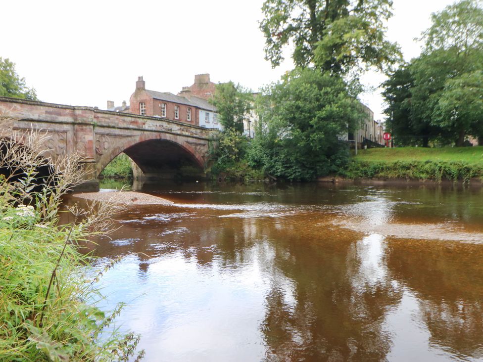A view of a river with a stone bridge and buildings at Sands Green Appleby-In-Westmorland