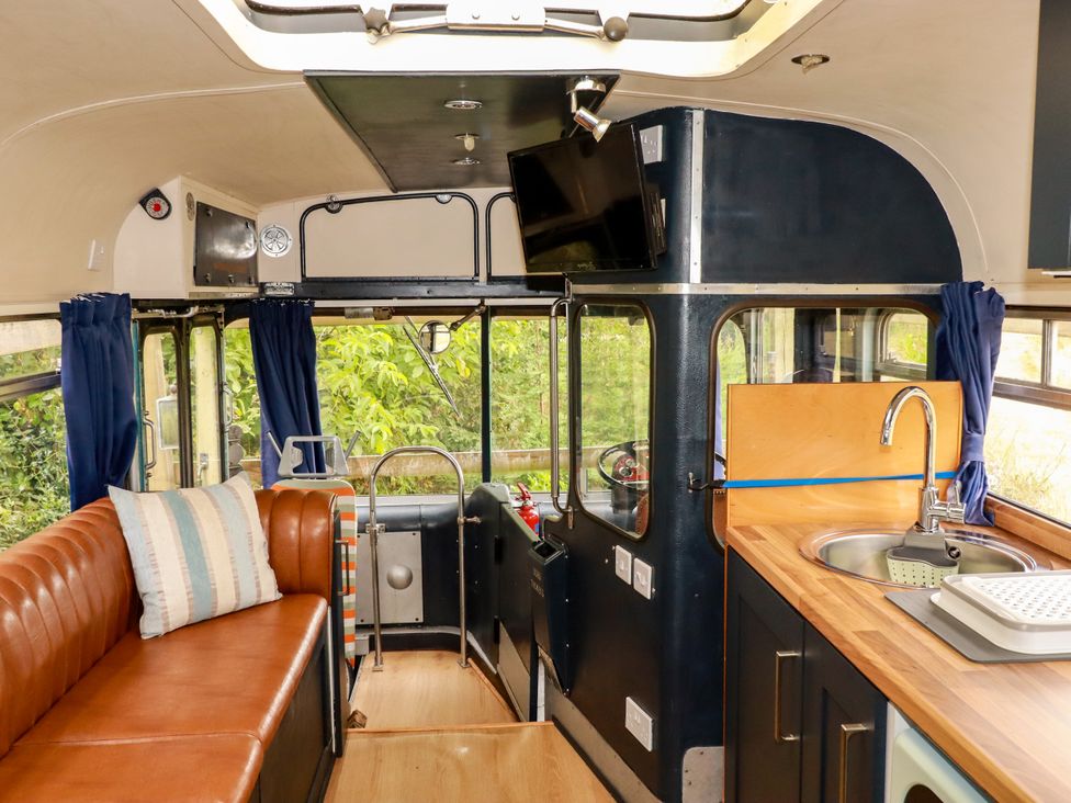 A living room with a sofa and sink at Honey Bee Bus in Menheniot