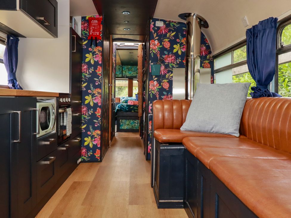 A living room with a couch and kitchen area at Honey Bee Bus in Menheniot