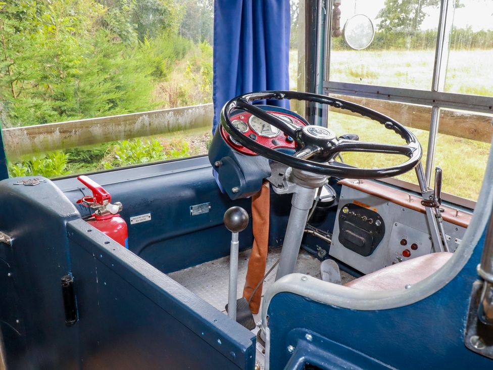 A bus interior with a steering wheel and dashboard at Honey Bee Bus Menheniot