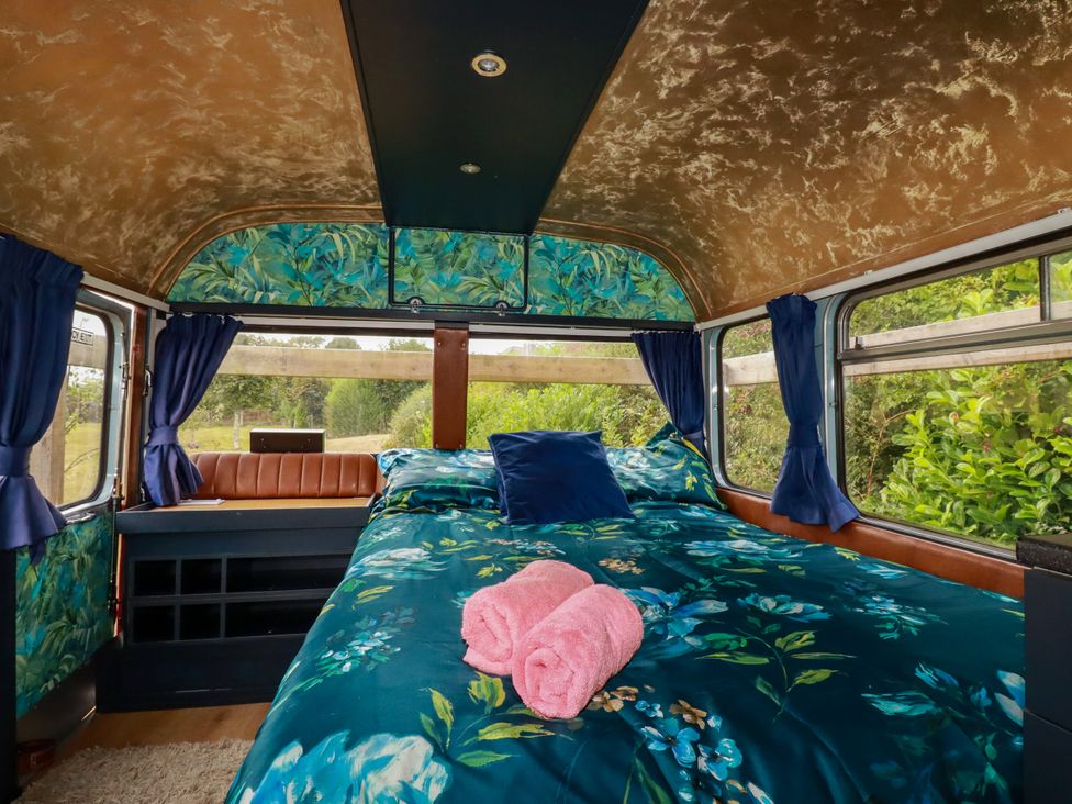 A bedroom with a bed and pillows in Honey Bee Bus Menheniot