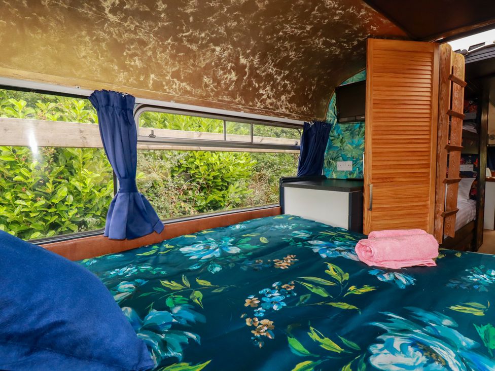A bedroom with a bed and window at Honey Bee Bus in Menheniot