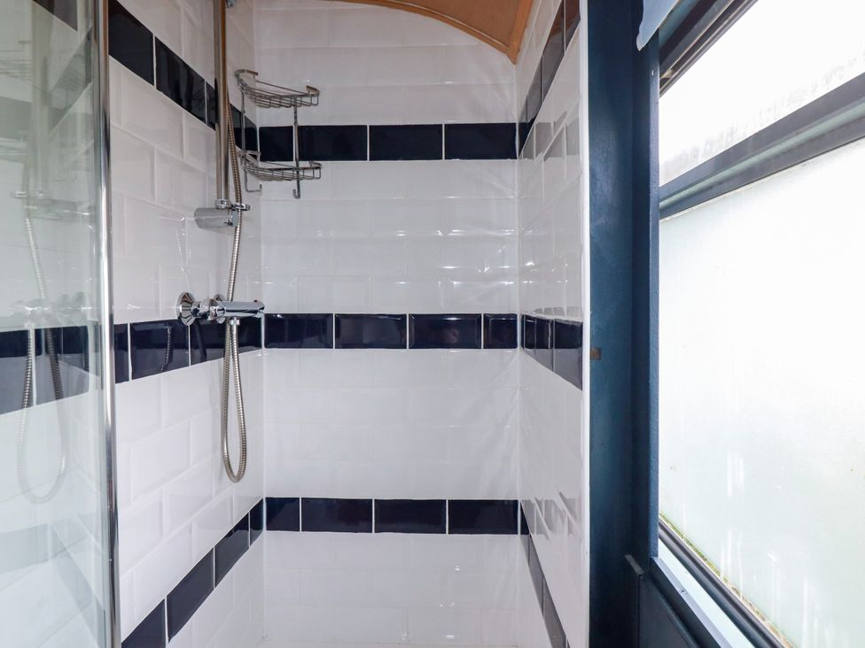 A shower with tiles and a window at Honey Bee Bus Menheniot