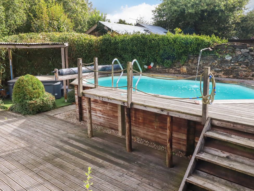 An outdoor area with a swimming pool and wooden decking at Honey Bee Bus in Menheniot