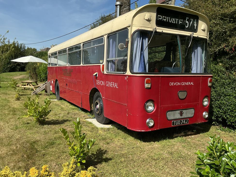 A red bus with a private sign in a garden area at Honey Bus in Menheniot