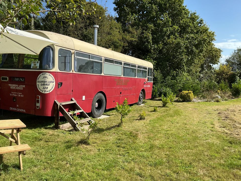 A red bus in a garden at Honey Bus in Menheniot