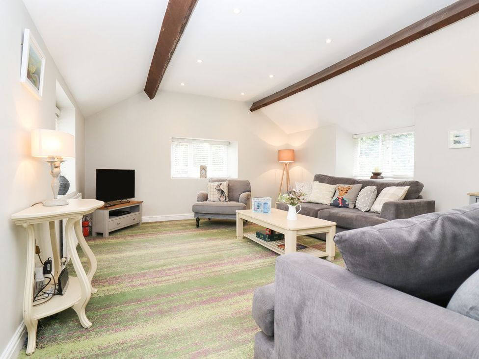 A living room with a sofa and coffee table at Peewit Barn in Moreton-in-Marsh