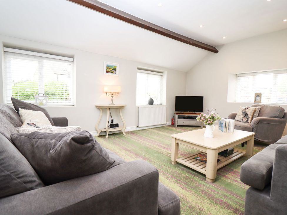 A living room with a sofa and coffee table at Peewit Barn in Moreton-in-Marsh