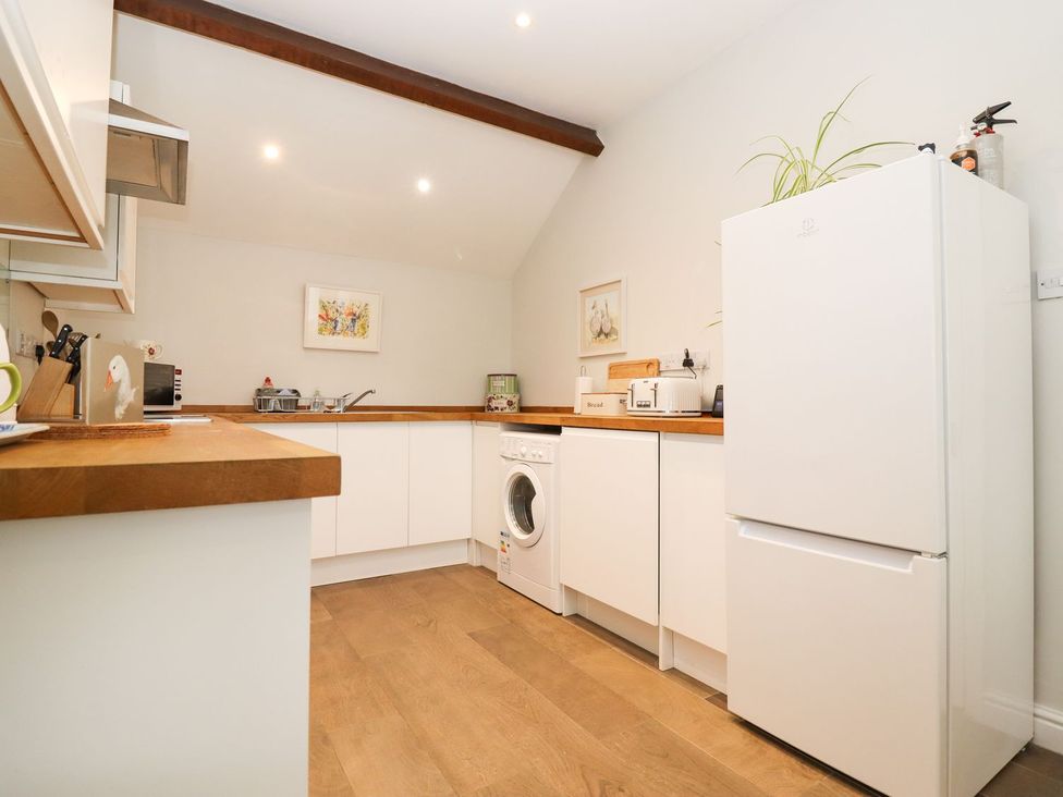 A kitchen with white cabinets and appliances at Peewit Barn in Moreton-in-Marsh
