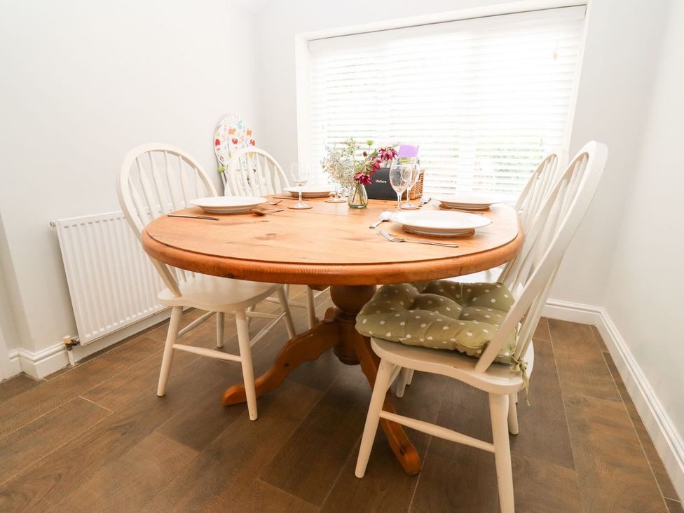A dining room with a round wooden table and four chairs at Peewit Barn in Moreton-in-Marsh