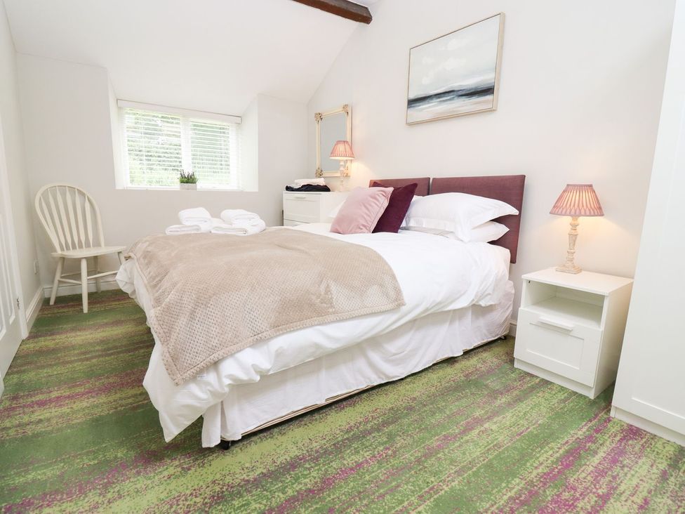 A bedroom with a bed and chair at Peewit Barn in Moreton-in-Marsh