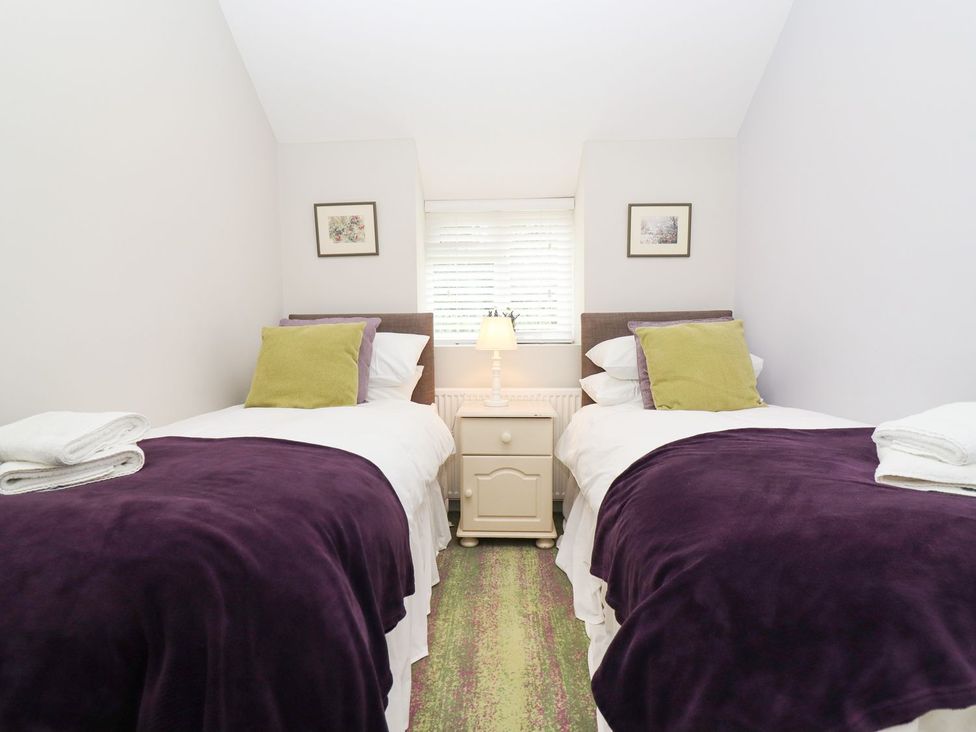 A bedroom with two beds and a bedside table at Peewit Barn in Moreton-in-Marsh