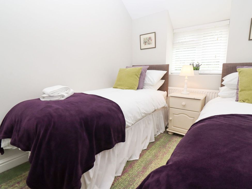 A bedroom with two beds and a nightstand at Peewit Barn Moreton-in-Marsh
