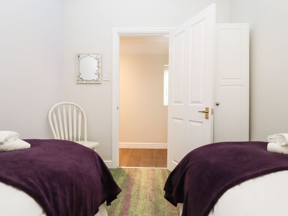 A bedroom with two beds and a chair at Peewit Barn in Moreton-in-Marsh