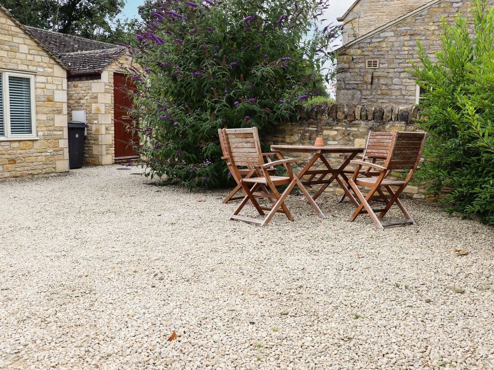 An outdoor seating area with a table and chairs at Peewit Barn Moreton-in-Marsh