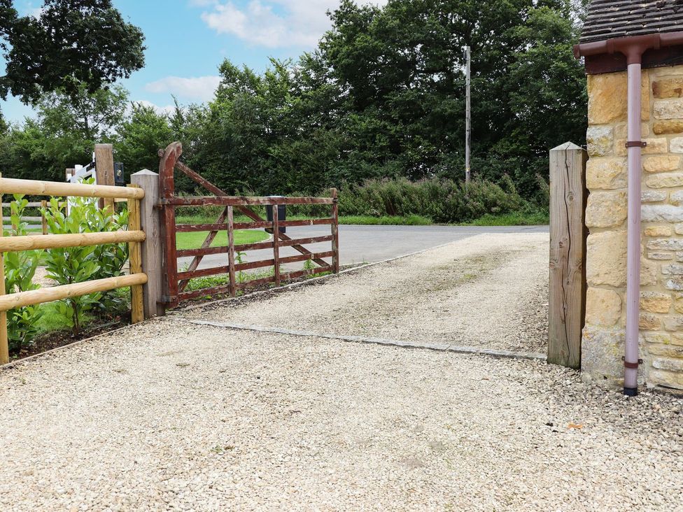 A gravel driveway with a gate leading to a road at Peewit Barn in Moreton-in-Marsh