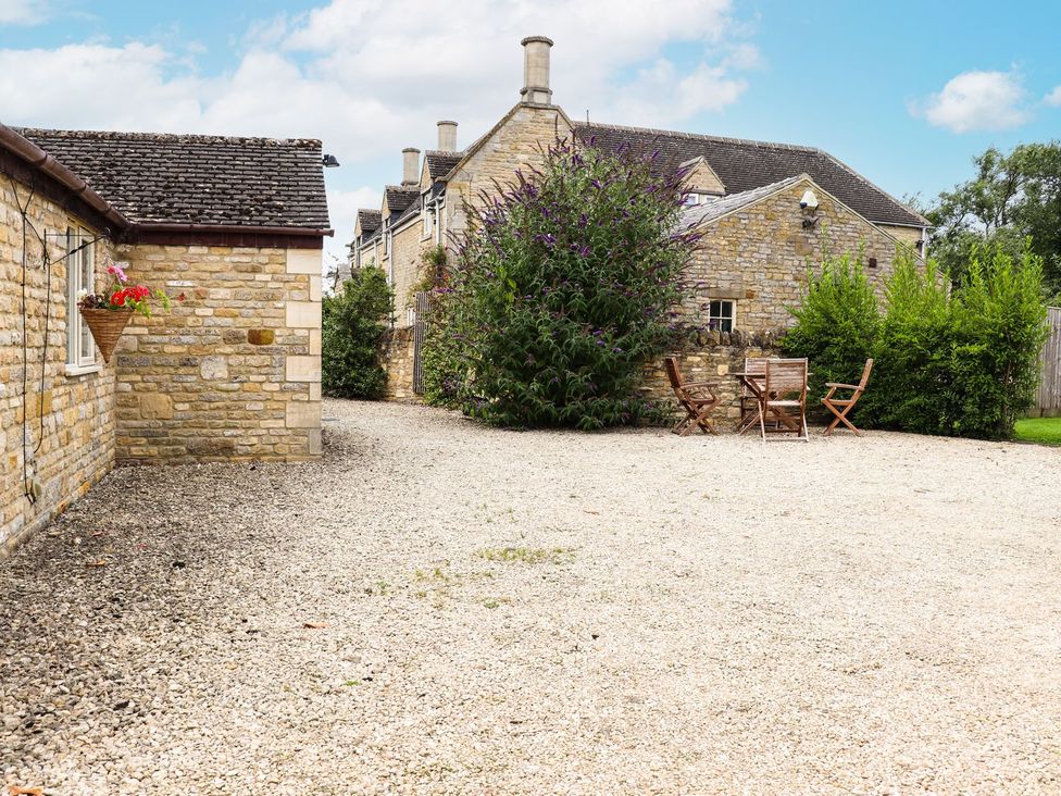 An outdoor area with gravel and wooden furniture at Peewit Barn Moreton-in-Marsh