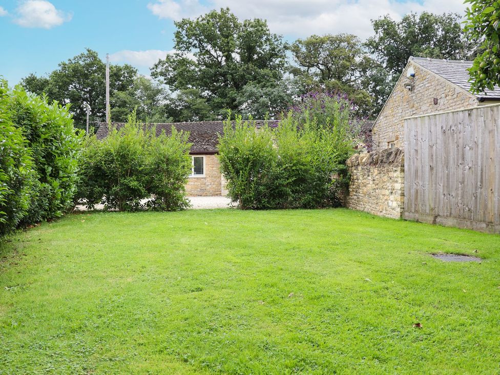 A garden area with grass and hedges at Peewit Barn in Moreton-in-Marsh