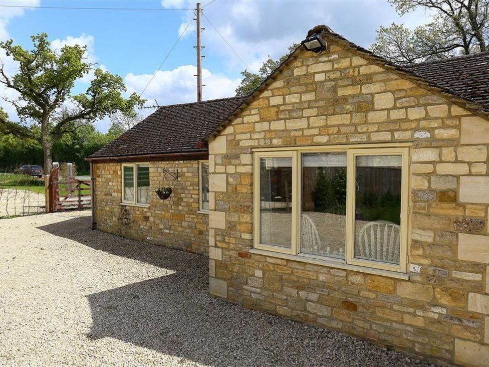 An outdoor area with a stone building and gravel at Peewit Barn in Moreton-in-Marsh