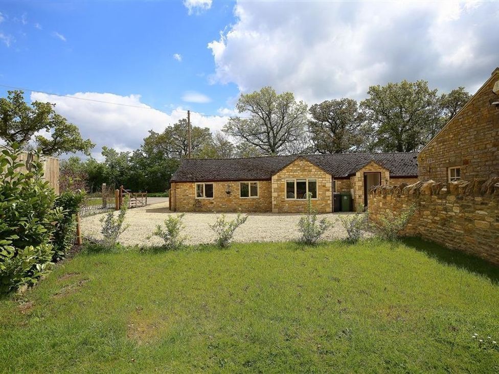 An outdoor area with a stone building and gravel driveway at Peewit Barn in Moreton-in-Marsh