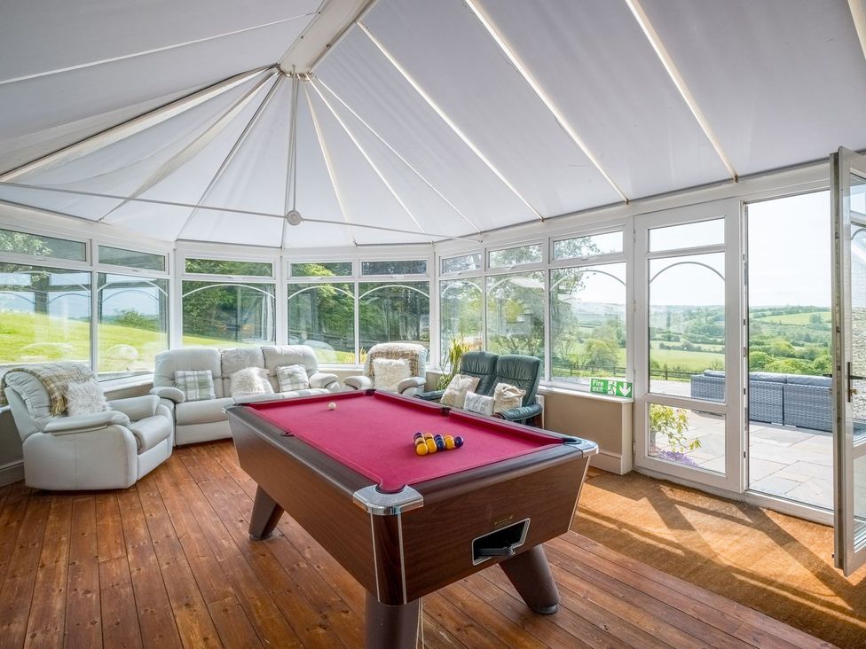 A conservatory with a pool table and seating area at Blaenachddu in Newcastle Emlyn