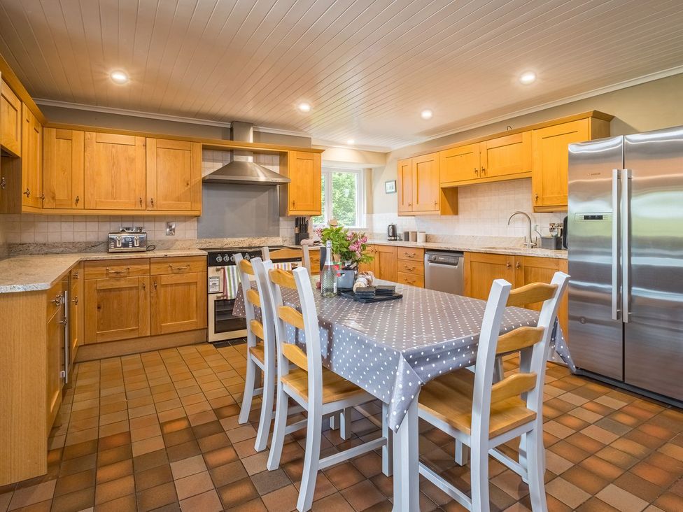 A kitchen with wooden cabinets and a table at Blaenachddu Newcastle Emlyn