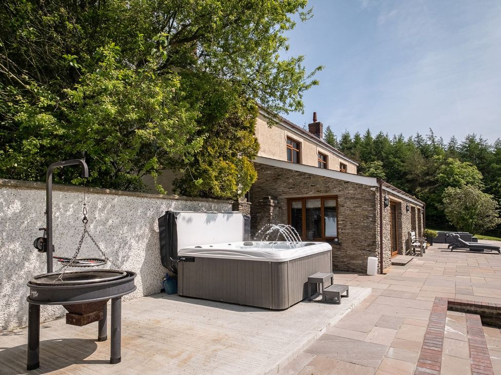 An outdoor area with a hot tub and fire pit at Blaenachddu Newcastle Emlyn