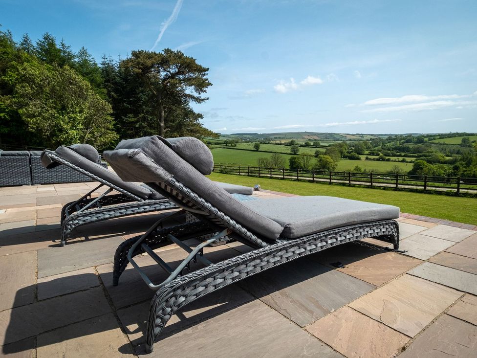 Two lounge chairs on a patio with a green landscape view at Blaenachddu Newcastle Emlyn